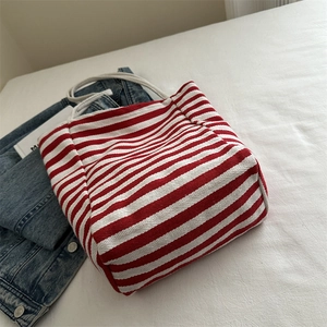 Minimalist red and white striped canvas tote bag with woven handles on white fabric