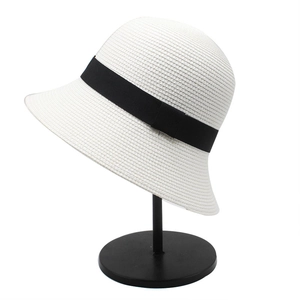 Detail of white straw bucket hat with black grosgrain ribbon bow on a display stand