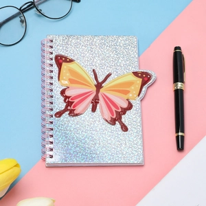 Close-up of a spiral notebook with a colorful glitter butterfly cover and pink coil