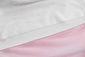 Detailed close-up of smooth white satin and pink mesh fabric textures for the dress