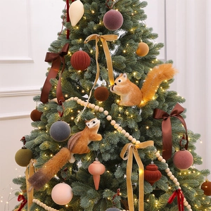 Plush Christmas squirrel ornaments and colorful velvet balls on a lit Christmas tree