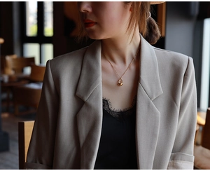 Close-up of minimalist hollow teardrop pendant necklace in gold finish on female model