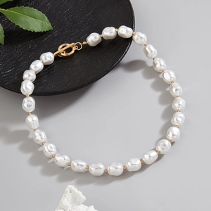 Close-up of baroque pearl necklace with golden OT buckle on a minimalist black tray