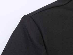 Close-up of the black blazer shoulder area showing twill fabric texture and stitching
