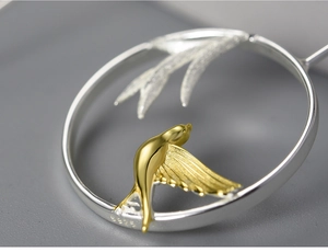 Macro shot of S925 sterling silver earring with golden bird and bamboo leaf details
