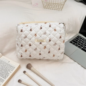 Detail of quilted white makeup bag with brown bear patterns and Sozakka woven label