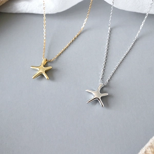 Elegant gold and silver S925 sterling silver starfish pendant necklaces on soft fabric