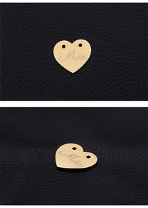 Macro detail of golden heart pendant with Mãe engraving on black leather background