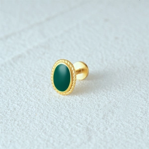 Macro shot of gold oval stud earring with deep green enamel and textured edges