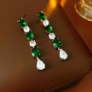 Gros plan de boucles d'oreilles pendantes avec cristaux verts et blancs sur cuir brun