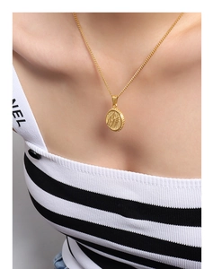 Close-up of golden wing engraved circular pendant on a geometric titanium steel chain