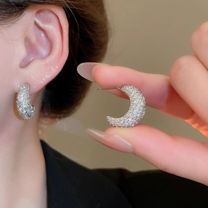 Macro detail of crescent moon earrings featuring micro-pave cubic zirconia on silver posts