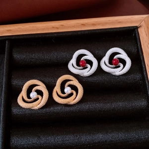 Close-up of vintage knot earrings in gold and silver with pearl and red bead details