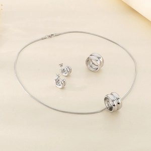 Macro view of silver layered round pendant necklace and earrings on beige cloth fabric