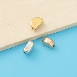 Close-up of bean-shaped stainless steel charms in gold, silver, and rose gold finishes