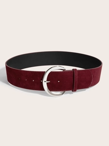 Détail macro d'une ceinture large en daim bordeaux avec boucle en métal argenté