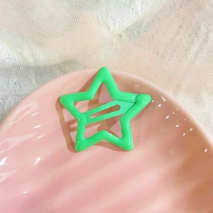 Star-shaped bright green snap hair clip for women on a pink shell plate with lace