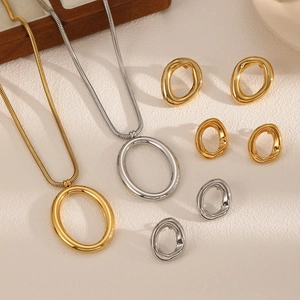 Detailed view of minimalist 18k gold and silver oval pendant necklaces and stud earrings