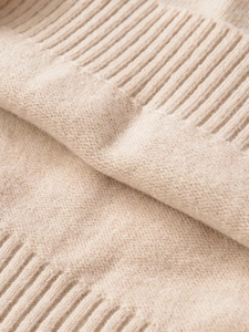 Close-up of beige knitted fabric showing fine ribbed texture and premium material quality