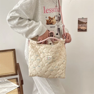Sac cabas beige matelassé avec motifs de dessins animés et bandoulière rose sur mannequin
