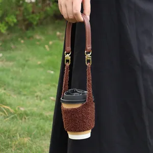 Detail of soft lamb wool coffee sleeve with brown leather handle and gold hardware