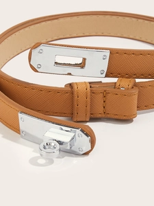 Macro shot of brown cross-grain leather belt showing silver metal buckle and stitching