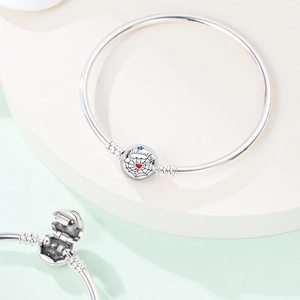 Macro shot of silver charm bracelet with Valiantly engraved bead and web design