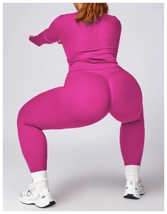 Deep squat pose showing rose red high waist yoga leggings and slim fit long sleeve top