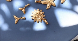 Artistic layout of gold seashell and sun pendants on a textured blue surface