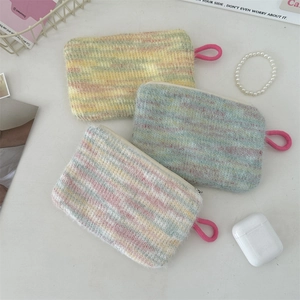Flat lay of colorful knitted plush pouches with pink zipper pulls on a clean desk