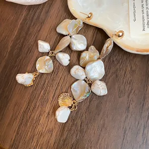Elegant irregular shell tassel drop earrings with silver pins on a white shell plate