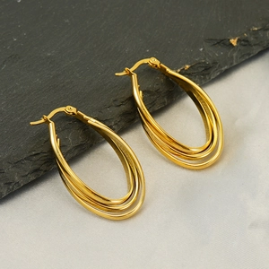 Detailed view of layered 18k gold-plated stainless steel hoop earrings on a stone background