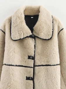 Dettaglio del cappotto in ecopelliccia beige con bordini neri, bottoni e etichetta taglia S
