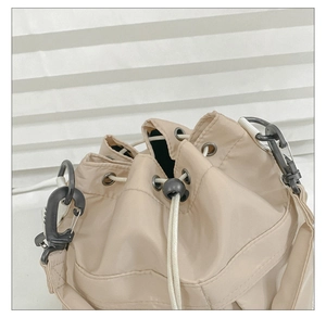 Detail of beige nylon bucket bag showing the drawstring closure and black durable hook