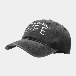 Close-up of 'mom LIFE' white embroidery on washed black cotton baseball cap fabric