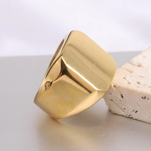 Macro side view of a polished golden square signet ring resting on a textured stone