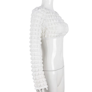 Detail of white long sleeve crop top featuring 3D popcorn texture and cutout neckline