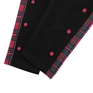 Detail of black casual trousers with tartan side panel and red button snap closures