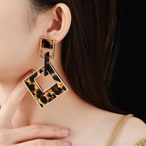 Detail view of square leopard print earrings on model with gold finish and alloy metal