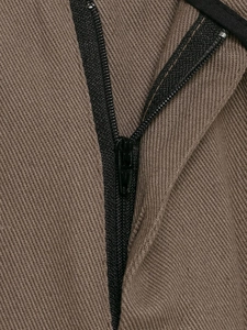 Détail macro de la fermeture éclair noire sur le tissu en sergé marron du pantalon