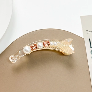 Close-up of resin fish-tail banana clip with embedded pearls and amber gemstones