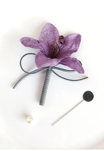 Detail of purple fabric boutonniere with velvet petals, grey cord handle, and pearl pin