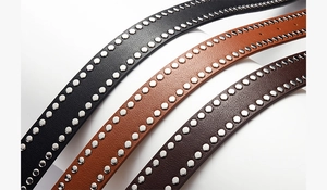 Detailed close-up of punk-style PU leather belts with double row silver metal rivets