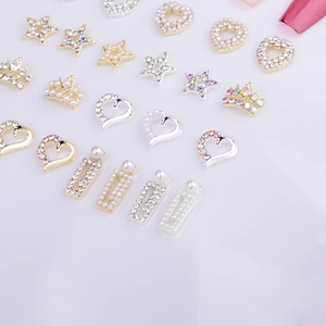 Détail de bijoux d'ongles 3D en métal avec cœurs et étoiles, strass et perles nacrées