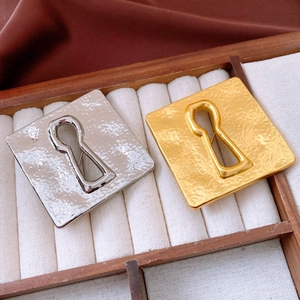 Macro detail of vintage hammered square brooches in gold and silver on a jewelry display tray