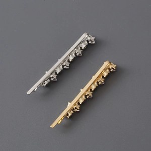 Detail of wavy gold and silver metal hair clips with rhinestone inlay on grey background