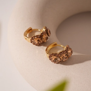 Macro detail of vintage gold hoop earrings with amber stones and small crystal accents