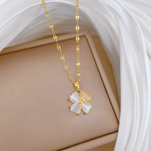 Macro view of gold clover pendant with mother of pearl and heart-shaped crystal inlay