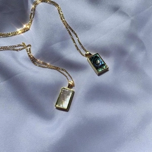Detailed macro of gold plated rectangle pendants with abalone and mother of pearl shells