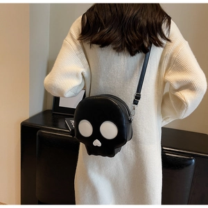 Detailed view of skull-shaped crossbody bag with heart nose on white sweater model